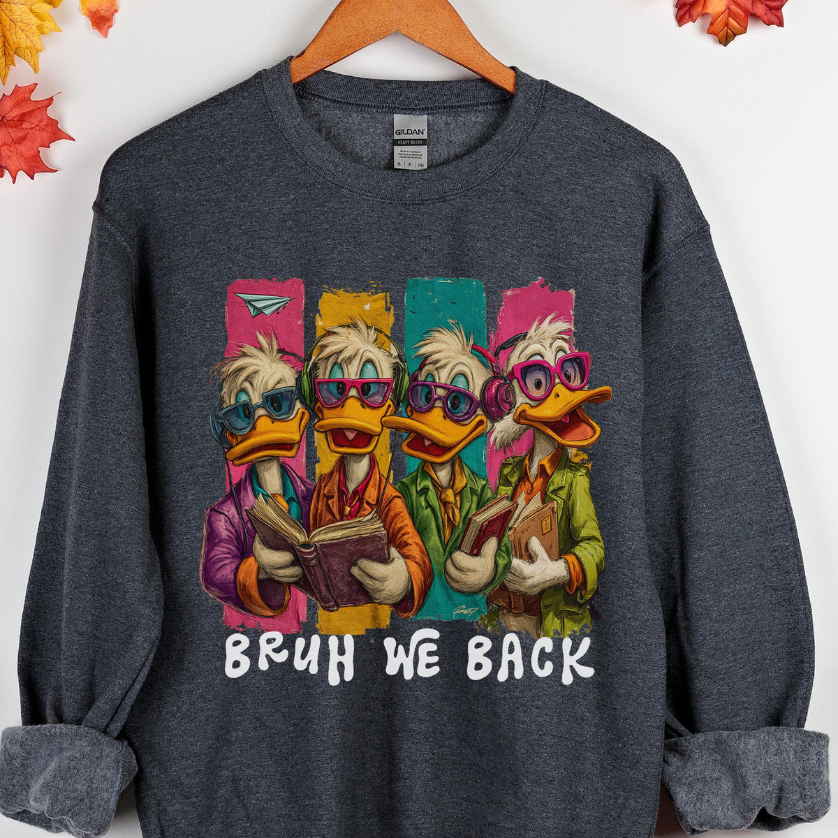 May include: Dark gray sweatshirt featuring a cartoon image of four ducks wearing glasses and holding books. The ducks are dressed in colorful outfits, with the text "BRUH WE BACK" in white below the image.