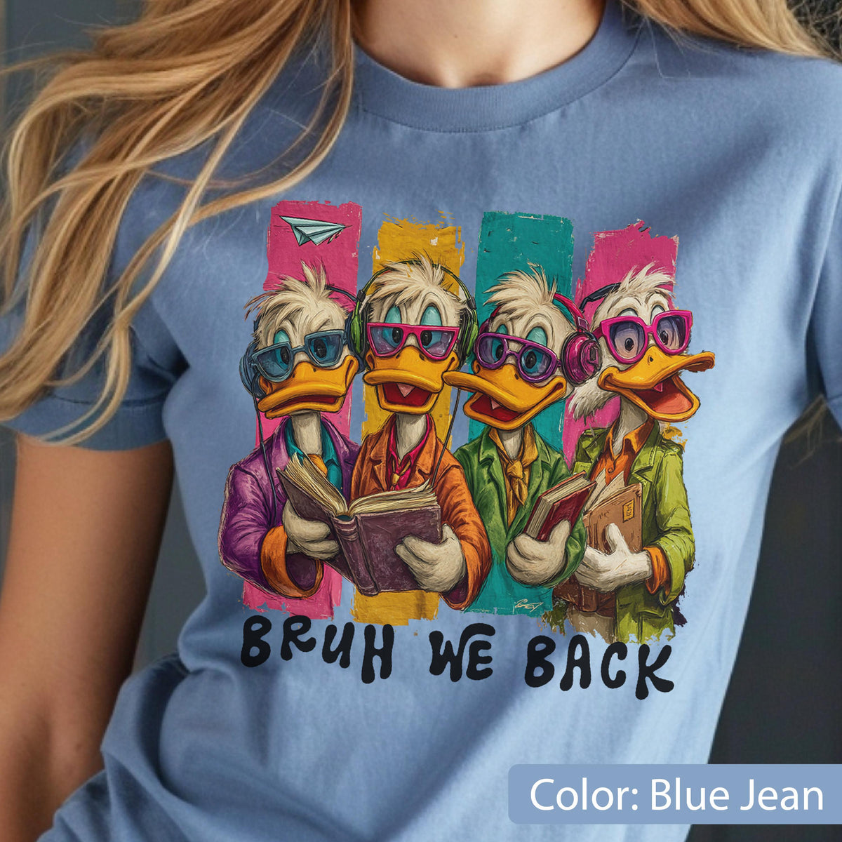 May include: Light blue t-shirt featuring a graphic of four cartoon ducks wearing glasses and headphones, each holding a book. The text "BRUH WE BACK" is below the graphic. The shirt is labeled "Color: Blue Jean".