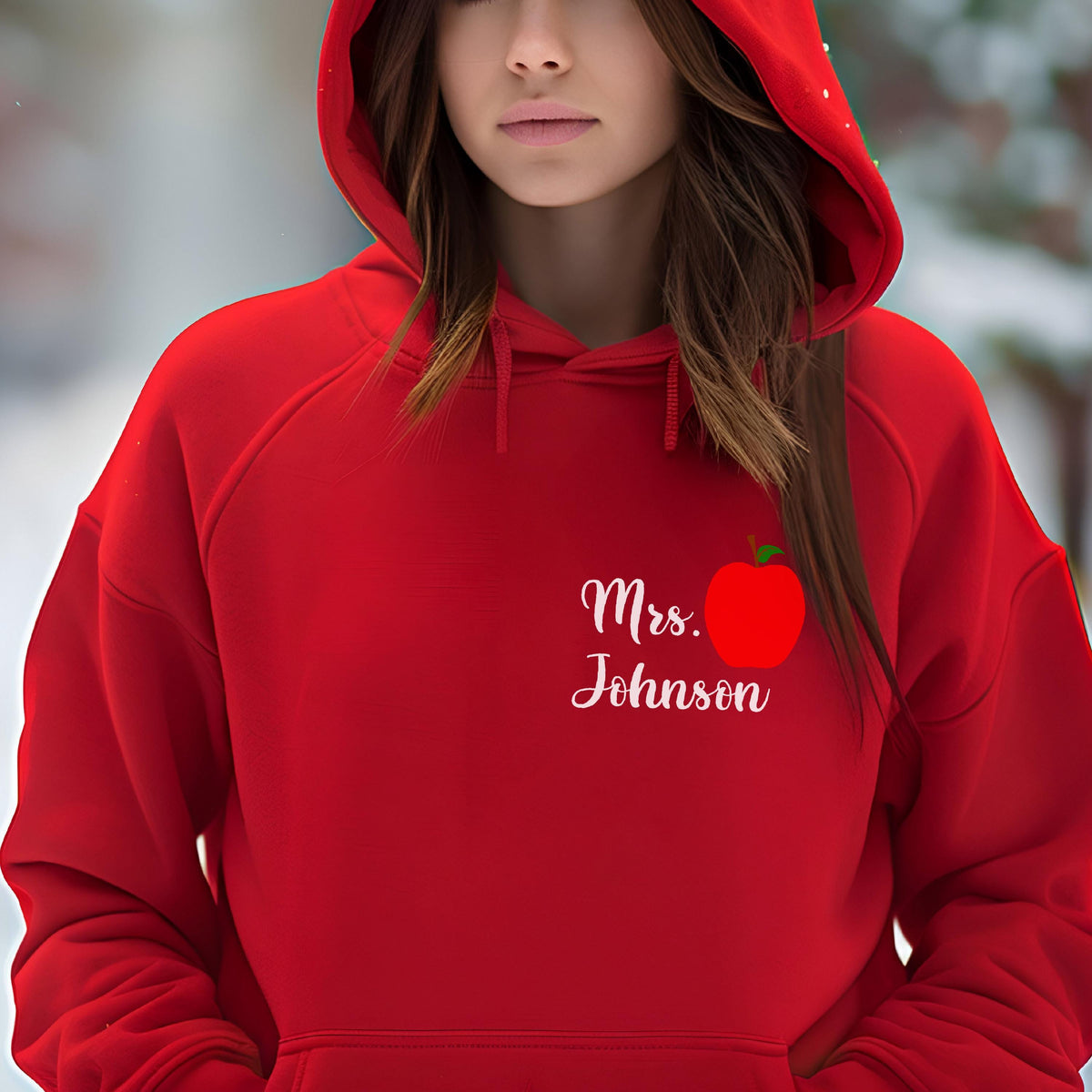 May include: A red hooded sweatshirt with the text "Mrs. Johnson" in white script, accompanied by a red apple graphic. The sweatshirt has a drawstring hood and a front pocket.