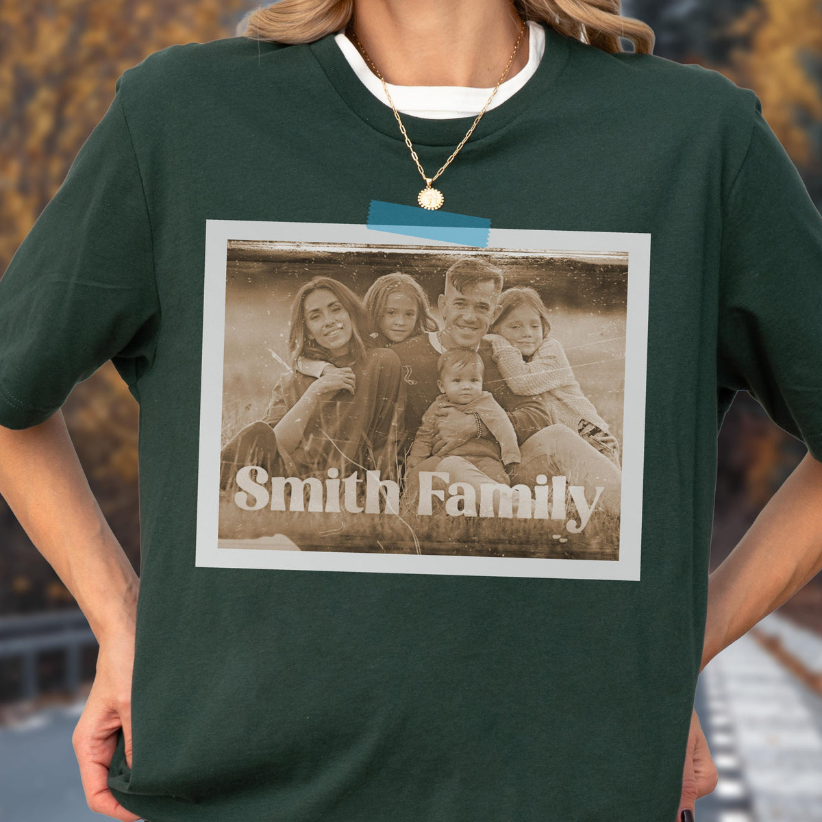 May include: Dark green t-shirt with a sepia-toned family photo attached with blue tape. The photo features a family of five with the words "Smith Family" printed at the bottom. The shirt has a white crew neck.