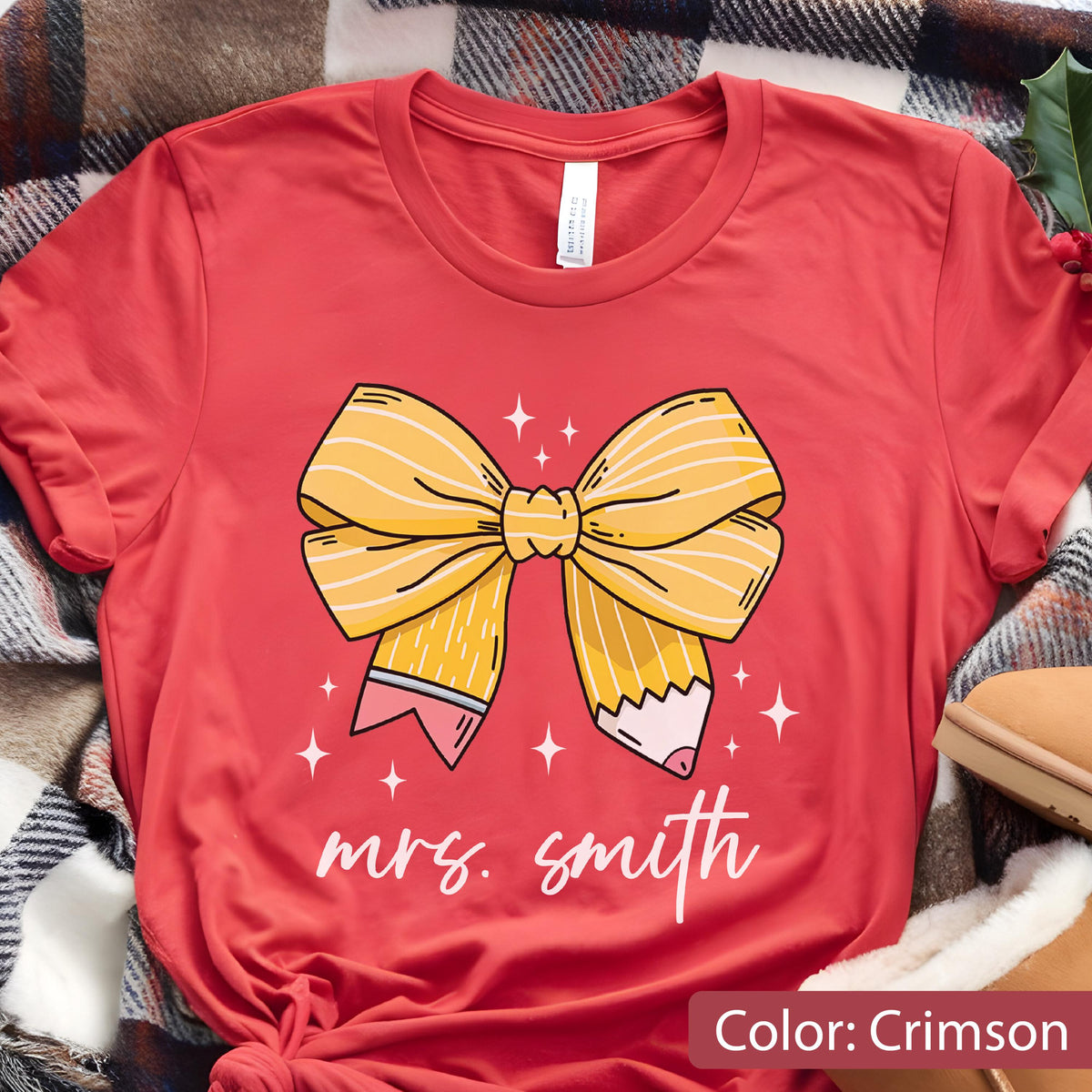 May include: Crimson-colored t-shirt featuring a yellow pencil bow design with the text "mrs. smith" in white. The bow has pencil-shaped ends with pink erasers. White star accents surround the bow.