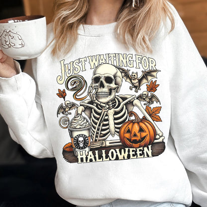 May include: A white crewneck sweatshirt featuring a graphic of a skeleton resting its chin on its hand. The design includes a coffee cup labeled 'Scarebucks', a jack-o'-lantern, bats, autumn leaves, and the text 'JUST WAITING FOR HALLOWEEN'.