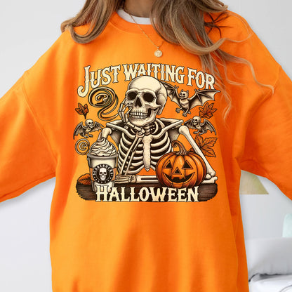 May include: A bright orange sweatshirt featuring a graphic print of a skeleton resting its chin on its hand. The design includes a pumpkin, bats, autumn leaves, and a coffee cup with a skull logo. The text reads JUST WAITING FOR HALLOWEEN.