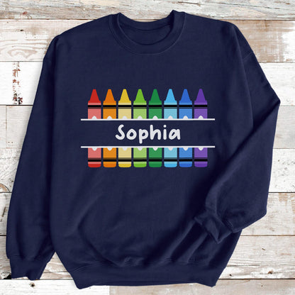 May include: Navy blue sweatshirt featuring a colorful crayon design. The design includes a row of crayons above and below the name "Sophia" in white, with a rainbow of colors. The sweatshirt is a comfortable, casual garment.