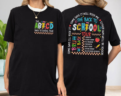 May include: Black t-shirt with a white neckline featuring colorful text and graphics. The front of the shirt says "THE ABZCD BACK TO SCHOOL TOUR". The back of the shirt says "THE BACK TO SCHOOL TOUR" with a list of school-related activities.