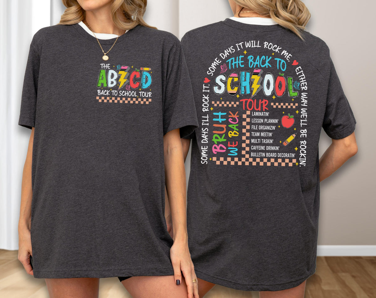 May include: Dark gray t-shirt with a white collar featuring colorful text and graphics. The front says "THE ABZCD BACK TO SCHOOL TOUR." The back has a school-themed design with phrases like "Some days I'll rock it" and "Bruh we back."