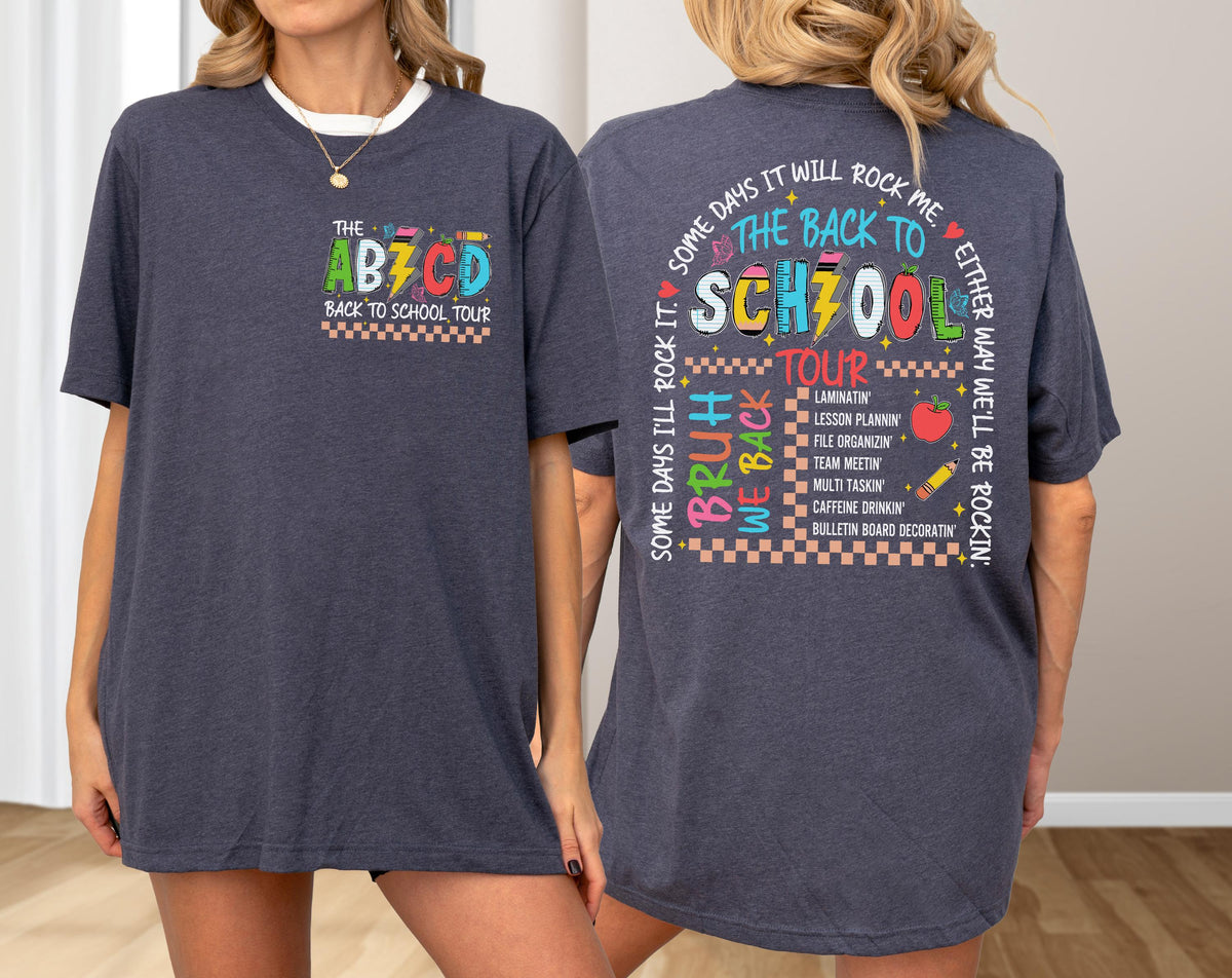 May include: Dark blue t-shirt with the text "THE ABZCD BACK TO SCHOOL TOUR" on the front pocket. The back of the shirt features the text "THE BACK TO SCHOOL TOUR" with a list of school-related activities. The shirt has a crew neck and short sleeves.