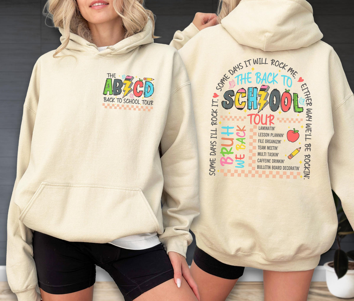 May include: A cream-colored hoodie with a front pocket and a hood. The front features the text "THE ABCD BACK TO SCHOOL TOUR" in colorful letters. The back displays "THE BACK TO SCHZOOL TOUR" with a list of school-related tasks and the phrase "SOME DAYS I'LL ROCK IT".