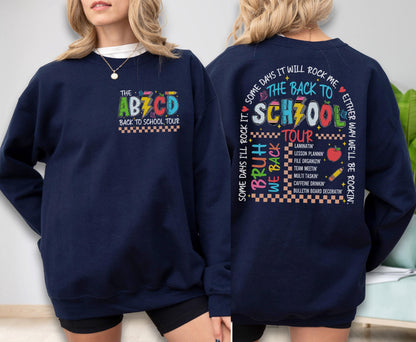 May include: Navy blue sweatshirt with the text "THE ABZCD BACK TO SCHOOL TOUR" on the front. The back of the sweatshirt features the text "THE BACK TO SCHZOOL TOUR" with various school-related phrases and graphics. A fun, colorful design.