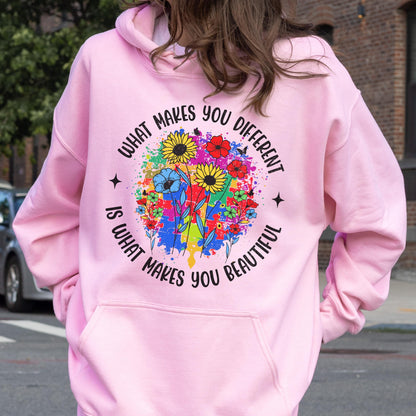 May include: A light pink hoodie with a front pocket and drawstring hood. The back features a colorful floral design with the text "WHAT MAKES YOU DIFFERENT IS WHAT MAKES YOU BEAUTIFUL" in a circular arrangement.