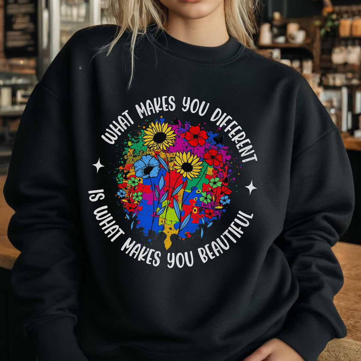 May include: Black sweatshirt with a colorful floral design. The design includes sunflowers, blue flowers, and other colorful blooms. The text "WHAT MAKES YOU DIFFERENT IS WHAT MAKES YOU BEAUTIFUL" is printed around the floral design.