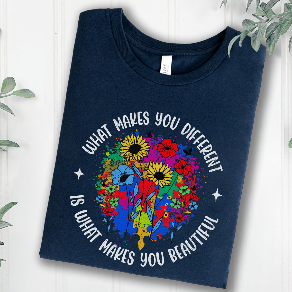 May include: Navy blue t-shirt with a floral design and the text "WHAT MAKES YOU DIFFERENT IS WHAT MAKES YOU BEAUTIFUL". The design features sunflowers, blue flowers, and other colorful blooms.