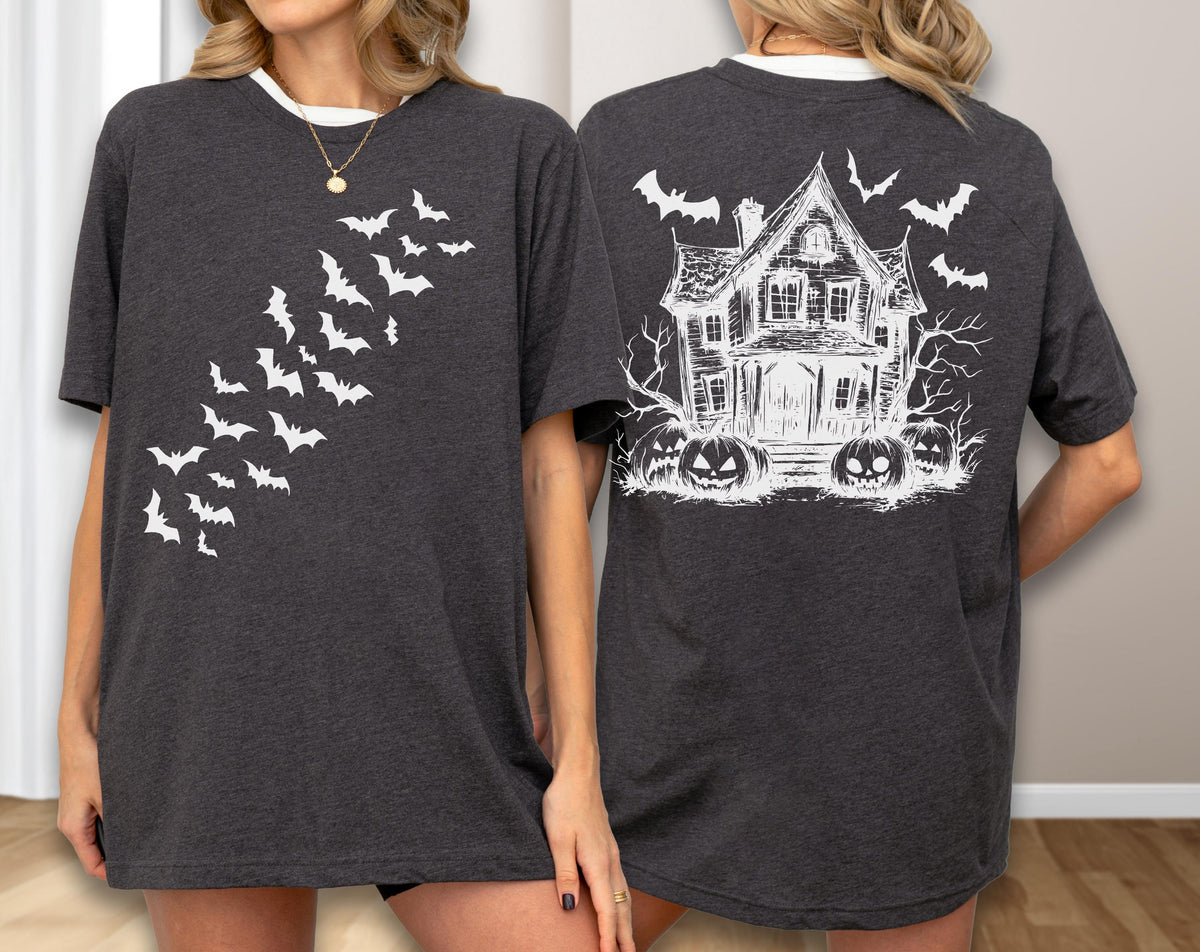 May include: Dark gray t-shirt with a white collar featuring a Halloween design. The front displays a flock of white bats in flight. The back showcases a haunted house, bats, and jack-o'-lanterns in white.
