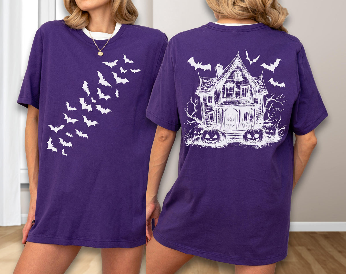 May include: Purple t-shirt with white graphics. The front features a flock of bats, while the back displays a haunted house, bats, and jack-o'-lanterns. The shirt has a white collar.