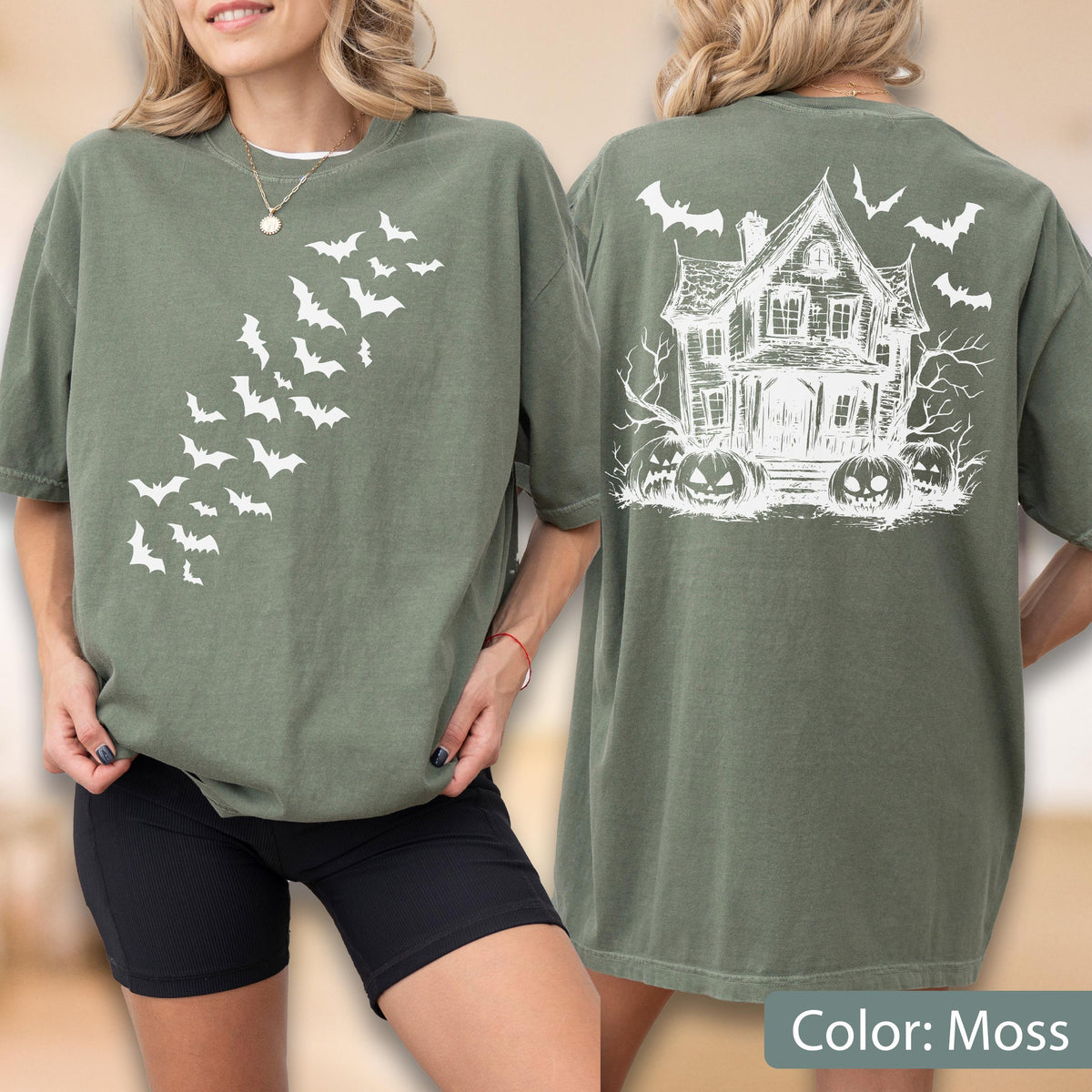 May include: An olive green t-shirt featuring a white graphic of a swarm of bats on the front. The back displays a white line-art illustration of a haunted house surrounded by bare trees, jack-o'-lanterns, and flying bats against the fabric.