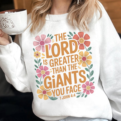 May include: White sweatshirt with the text "THE LORD IS GREATER THAN THE GIANTS YOU FACE" in orange and surrounded by pink, yellow, and orange flowers. The sweatshirt also has the Bible verse 1 John 4:4.