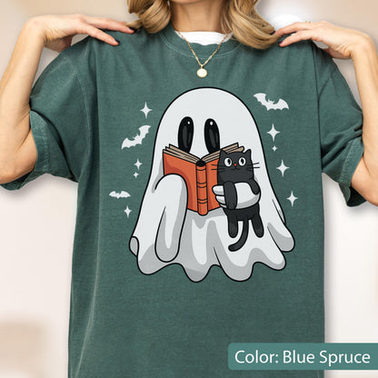 May include: Blue spruce t-shirt featuring a cartoon ghost reading a book with a black cat. The ghost is white with black eyes, holding an orange book. Bats and stars are scattered around the ghost. The text "Color: Blue Spruce" is at the bottom.