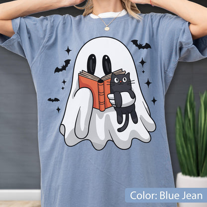 May include: Blue jean colored t-shirt featuring a cartoon ghost reading a book with a black cat. The ghost is white with black eyes and the cat is black. Bats and stars are scattered around the ghost.
