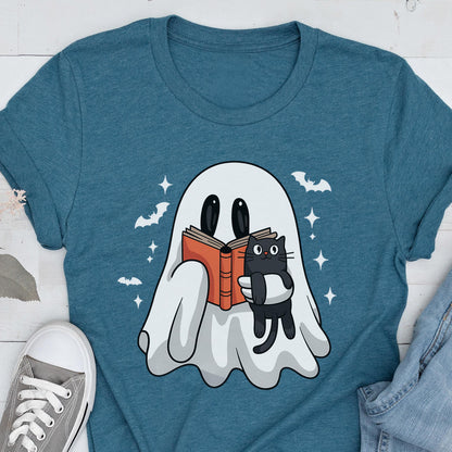 May include: A teal crew neck t-shirt featuring a graphic of a white ghost holding an open orange book and a small black cat. The design includes white stars and silhouettes of flying bats surrounding the ghost on the front of the garment.