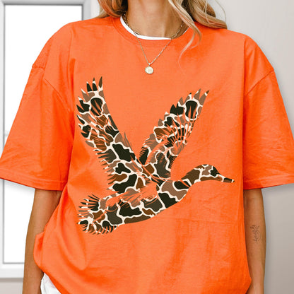 May include: A bright orange short-sleeve t-shirt featuring a large graphic of a flying duck. The duck is filled with a brown, black, and white animal print pattern. The shirt has a crew neckline and a loose, relaxed fit throughout the body.