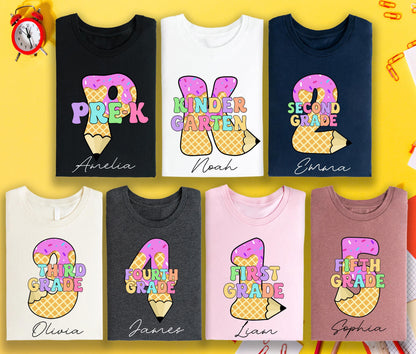 May include: A collection of t-shirts in various colors, each featuring a grade level design. The designs include the grade level, a pencil, and a name. The shirts are for Pre-K, Kindergarten, 2nd, 3rd, 4th, 1st, and 5th grade.