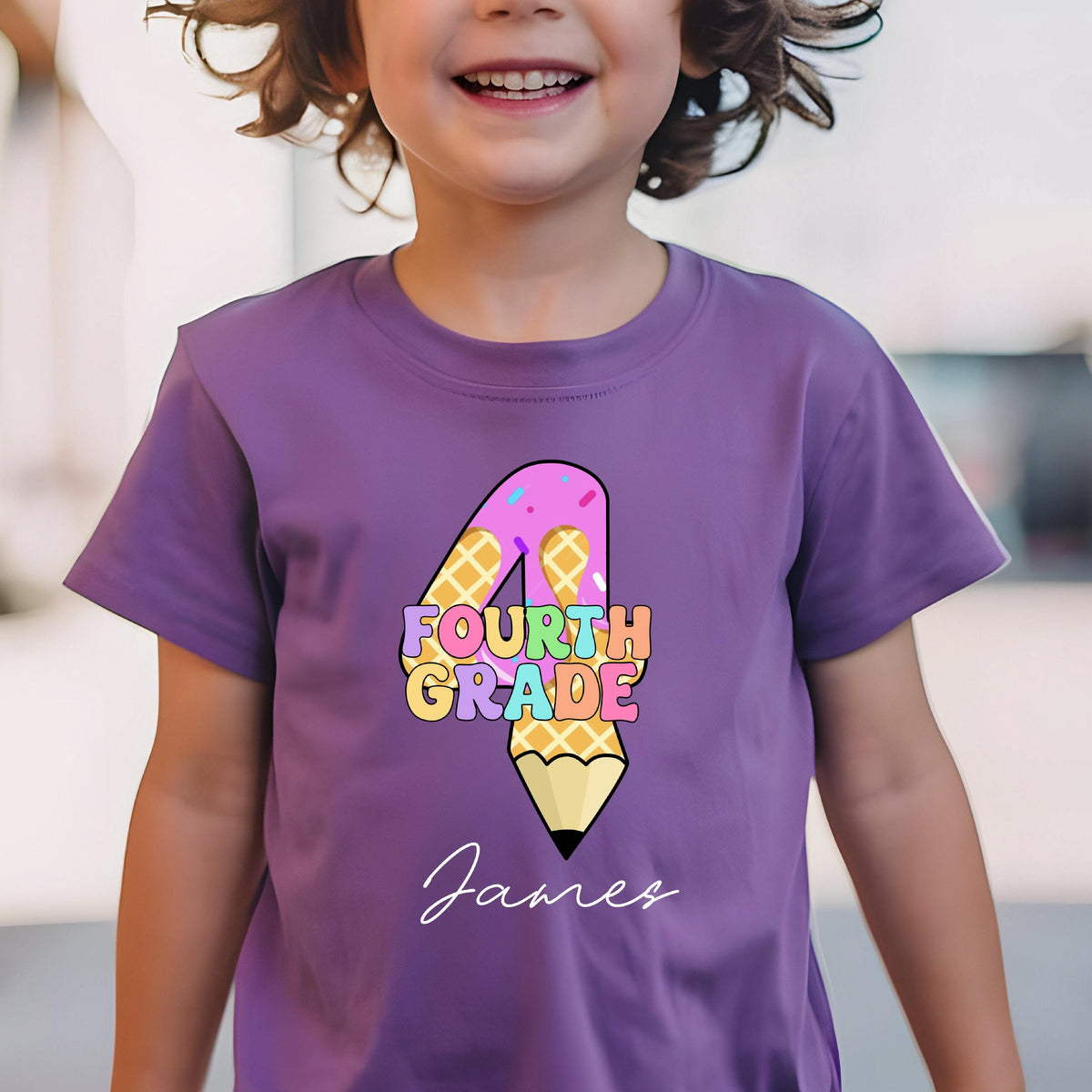 May include: A purple t-shirt featuring a colorful graphic for fourth grade. The design includes a number 4 with a waffle pattern, ice cream, and a pencil. The name "James" is written in cursive below the graphic.