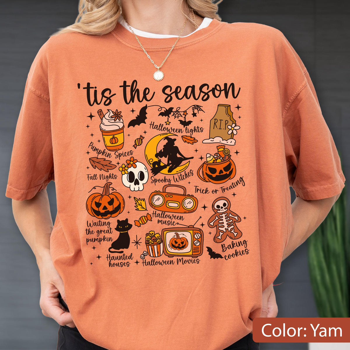 May include: An orange t-shirt featuring the text 'tis the season and various Halloween-themed illustrations including a pumpkin spice drink, a skull, a witch on a moon, a jack-o'-lantern, a black cat, a boombox, a television, and a skeleton cookie.