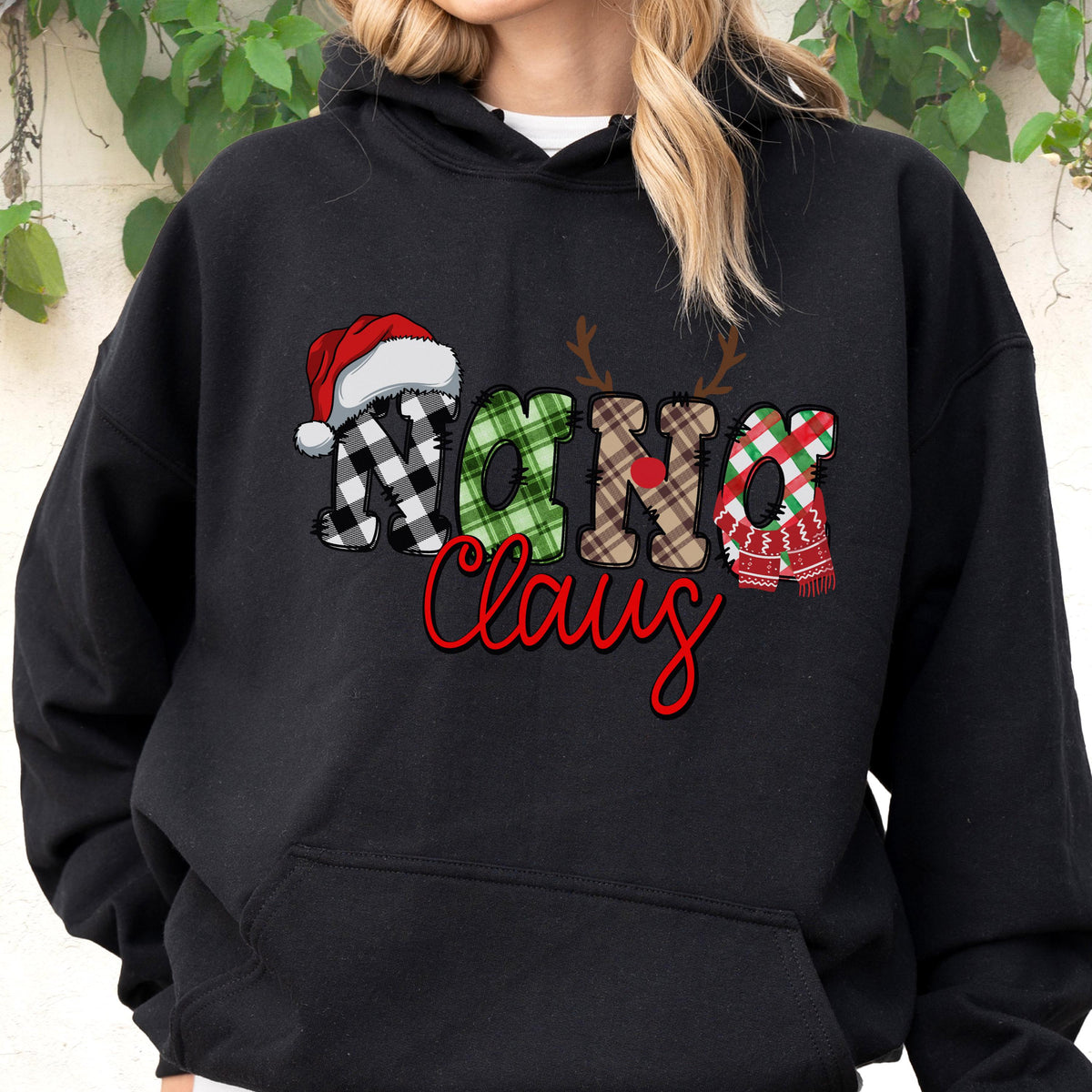 May include: Black hooded sweatshirt with the text "Nana Claus" in a festive design. The word "Nana" features a Santa hat, plaid patterns, and reindeer antlers. The word "Claus" is in red script.