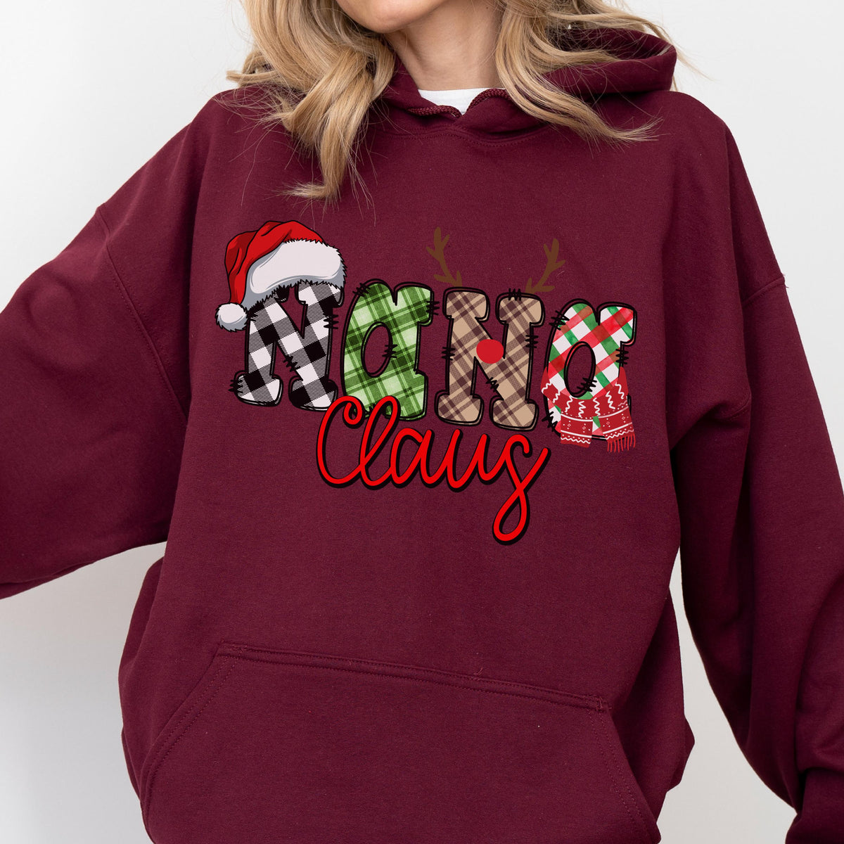 May include: Burgundy hoodie with a festive "Nana Claus" design. The text features a Santa hat, reindeer antlers, and plaid patterns in black and white, green, and red. The word "Claus" is in red script.