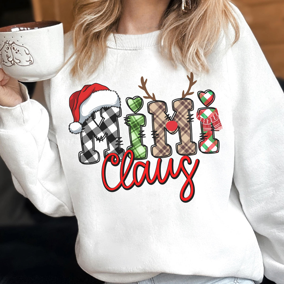 May include: White sweatshirt with the text "Mimi Claus" in a festive design. The letters are decorated with plaid patterns, a Santa hat, reindeer antlers, and hearts. A cozy holiday-themed apparel item.