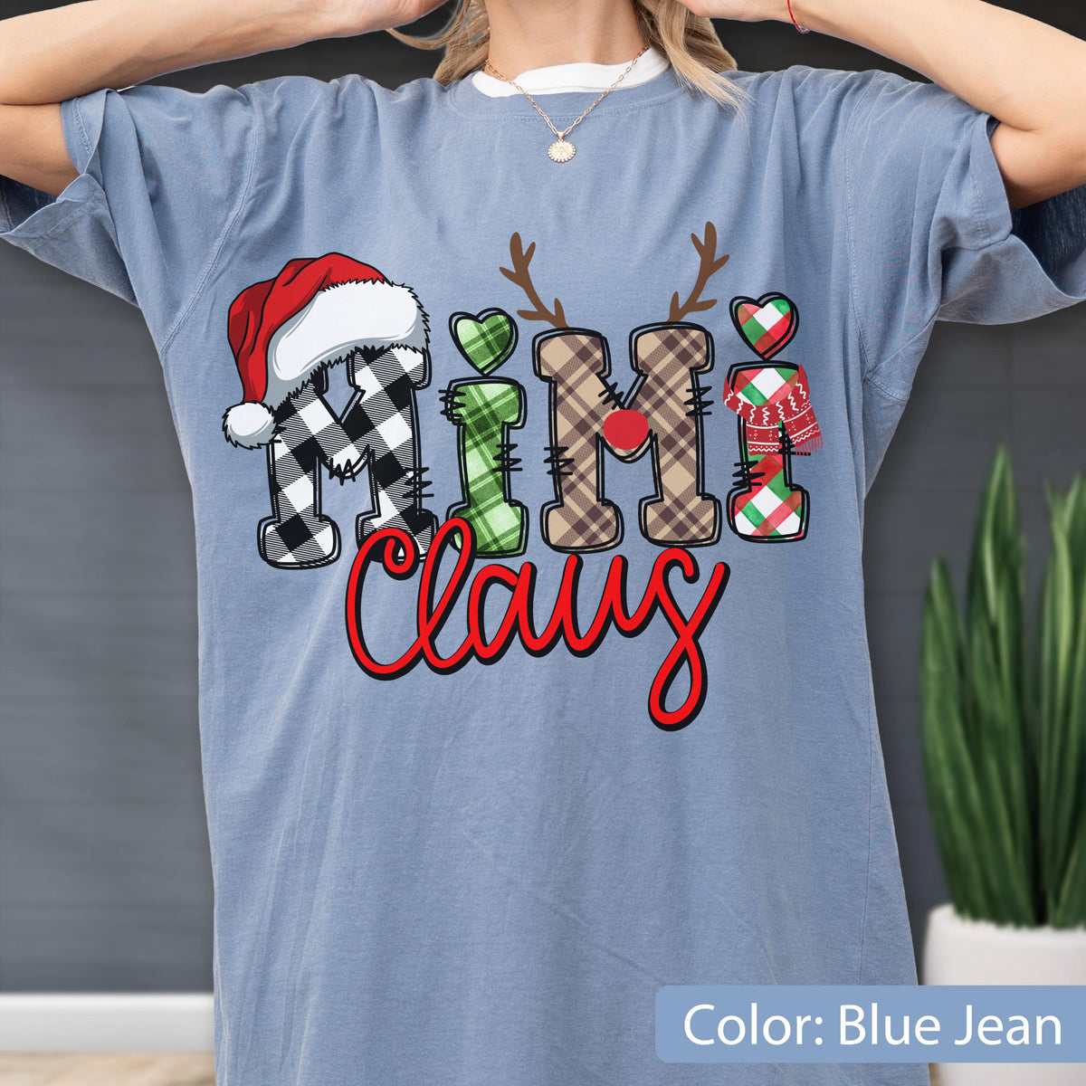 May include: A blue jean colored t-shirt featuring the text Mimi Claus. The letters are decorated with patterns including black and white buffalo plaid, green plaid, brown plaid, and red and green plaid. A red Santa hat, reindeer antlers, and a scarf are included.