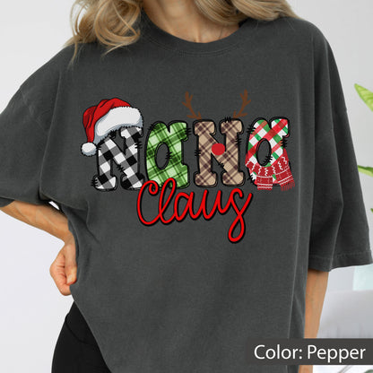 May include: A pepper-colored t-shirt featuring the text Nana Claus in a decorative font. The word Nana is styled with plaid patterns, a red Santa hat, reindeer antlers, and a red nose. The word Claus is written in a bold red script font.