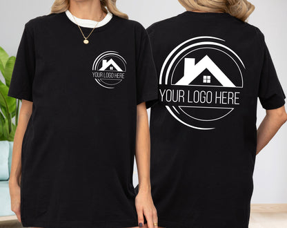 May include: Black t-shirt with a white collar and a white logo on the front and back. The logo features a house silhouette within a circular design, with the text "YOUR LOGO HERE" below it. The shirt is a casual wear item.