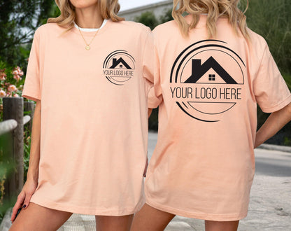 May include: Peach-colored t-shirts with a black logo featuring a house silhouette inside a circle, with the text "YOUR LOGO HERE". The design is on the front and back of the shirts. The shirts are short-sleeved and have a crew neck.