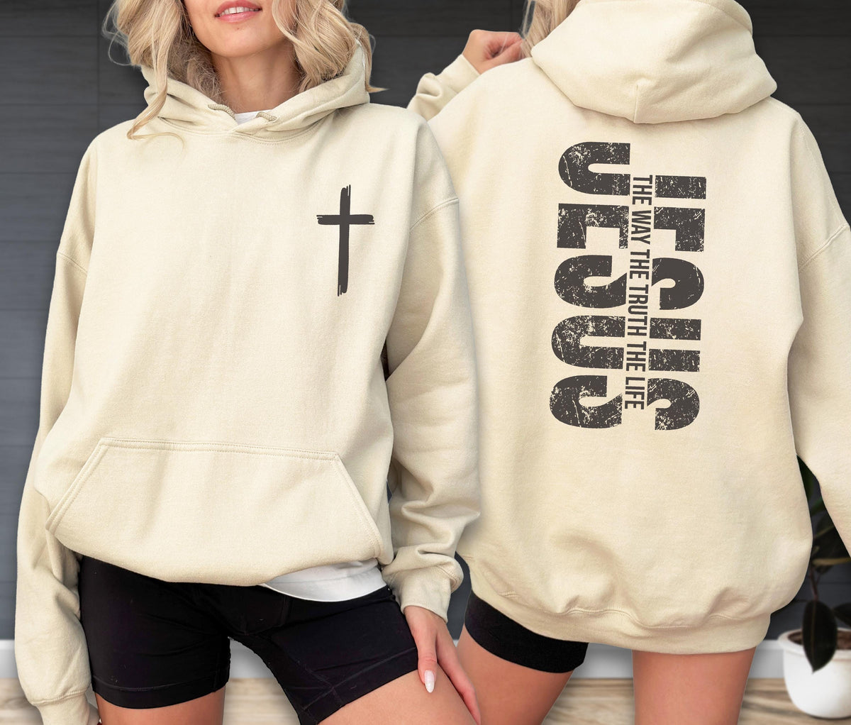 May include: Cream-colored hoodie with a black cross on the front and the word "JESUS" vertically printed on the back, along with the text "THE WAY THE TRUTH THE LIFE". The hoodie has a front pocket and a hood.
