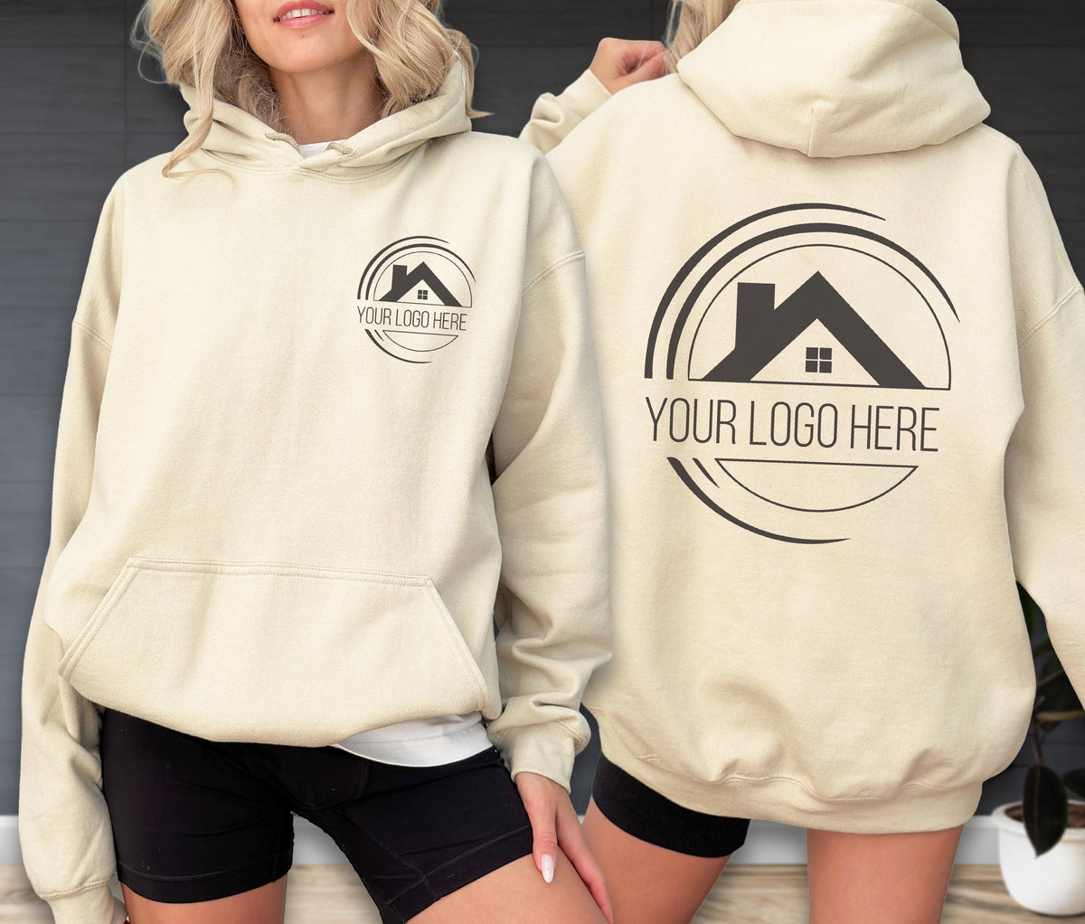 May include: Cream-colored hoodie with a front pocket and a hood. The front and back of the hoodie feature a black logo with a house silhouette and the text "YOUR LOGO HERE" in a semi-circle.