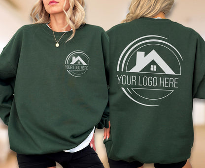 May include: Dark green sweatshirt with a white logo on the front and back. The logo features a house silhouette inside a circle with the text "YOUR LOGO HERE". The sweatshirt is a solid color and has a crew neck.
