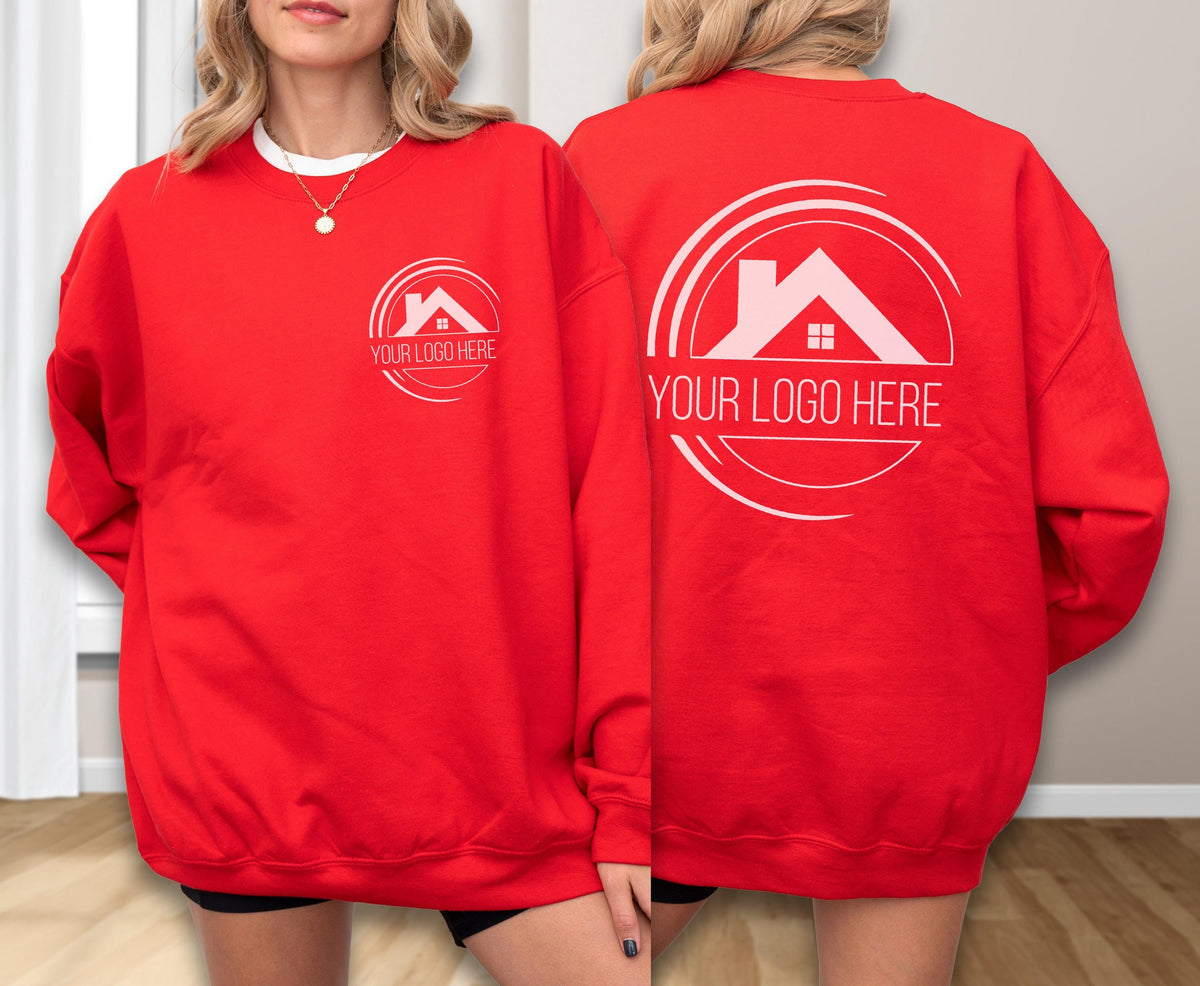 May include: A red sweatshirt with a white logo featuring a house silhouette and the text "YOUR LOGO HERE". The sweatshirt is displayed on a person. The logo is repeated on the front and back of the sweatshirt.