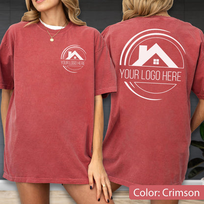 May include: Crimson-colored t-shirt with a white logo on the front and back. The logo features a house silhouette within a circular design, with the text "YOUR LOGO HERE" below. The shirt is short-sleeved and has a relaxed fit.