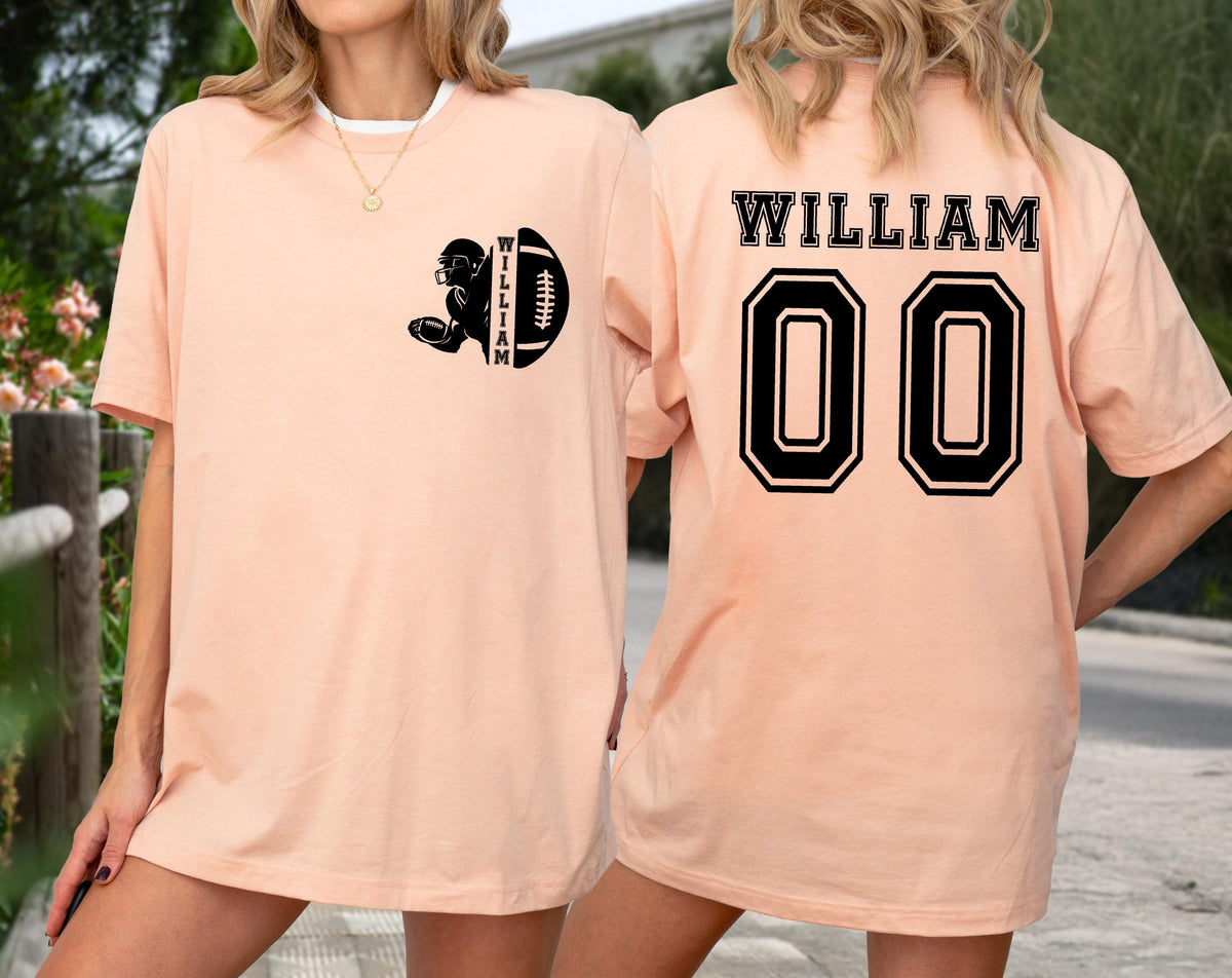 May include: Peach-colored t-shirt with a black football graphic and the name "WILLIAM" on the front and back. The back of the shirt also features the number "00" in a black, outlined font. The shirt is a casual, unisex style.