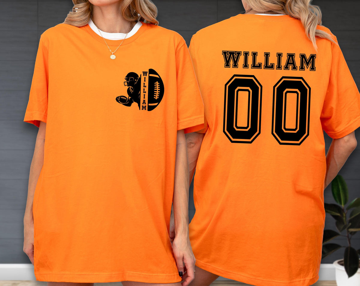 May include: Orange t-shirt with a football-themed design. The front features a black graphic of a football player and a football, with the name "WILLIAM" on the side. The back displays "WILLIAM" above the number "00" in black.