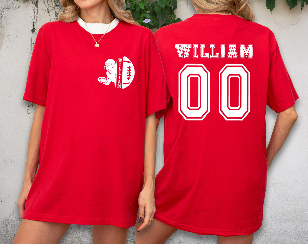May include: Red t-shirt with white accents. The front features a football graphic with the name "WILLIAM". The back of the shirt displays "WILLIAM" above the number "00". The shirt has a white collar.