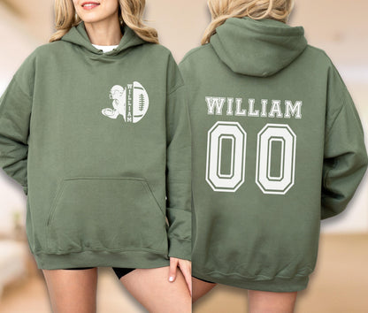May include: An olive green hooded sweatshirt featuring a white graphic on the front left chest of a football player silhouette and a football with the name WILLIAM. The back displays the name WILLIAM in white letters above the large white number 00.