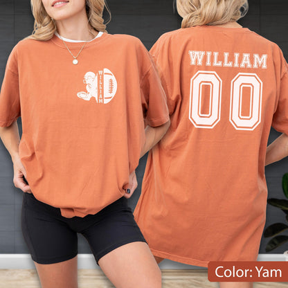 May include: A yam-colored t-shirt with a football design and the name "WILLIAM" and the number "00". The front of the shirt features a football graphic with the name "WILLIAM" vertically. The back of the shirt displays the name "WILLIAM" and the number "00".