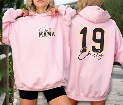 May include: A light pink hoodie with the text "Softball MAMA" on the front. The back of the hoodie features the number "19" in black with a yellow outline, and the name "Emily" in a script font. The hoodie has a front pocket and a hood.
