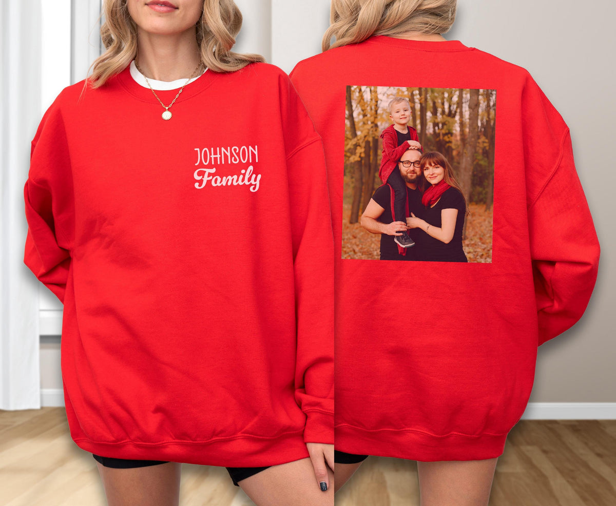 May include: A red sweatshirt with the text "Johnson Family" in white script on the front. The back of the sweatshirt features a family photo. The sweatshirt has a crew neck and long sleeves.