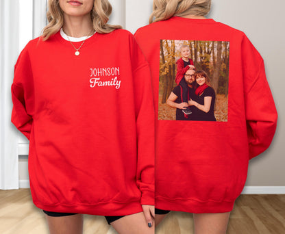 May include: A red sweatshirt with the text "Johnson Family" in white script on the front. The back of the sweatshirt features a family photo. The sweatshirt has a crew neck and long sleeves.