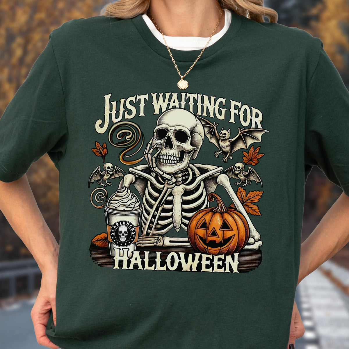 May include: Dark green t-shirt with a Halloween-themed graphic. The graphic features a skeleton with a coffee cup, pumpkin, and bats, with the text "Just Waiting For Halloween".