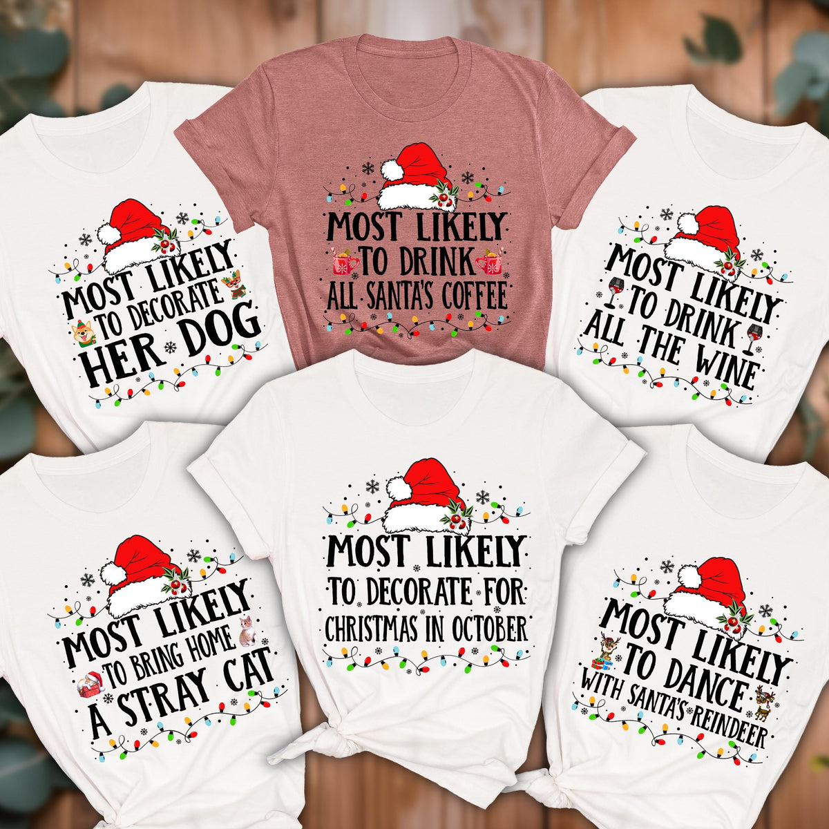 May include: A collection of white and mauve t-shirts with Christmas-themed text. Each shirt features a Santa hat and string lights. The phrases include "Most Likely to Decorate Her Dog," "Drink All Santa's Coffee," and "Bring Home a Stray Cat."