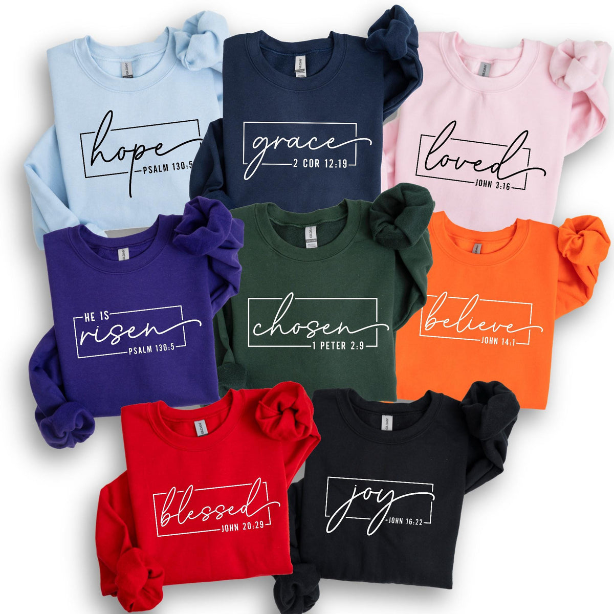 May include: A collection of long-sleeved sweatshirts in various colors, including light blue, navy, pink, purple, green, orange, red, and black. Each sweatshirt features a white script word design with a corresponding Bible verse.